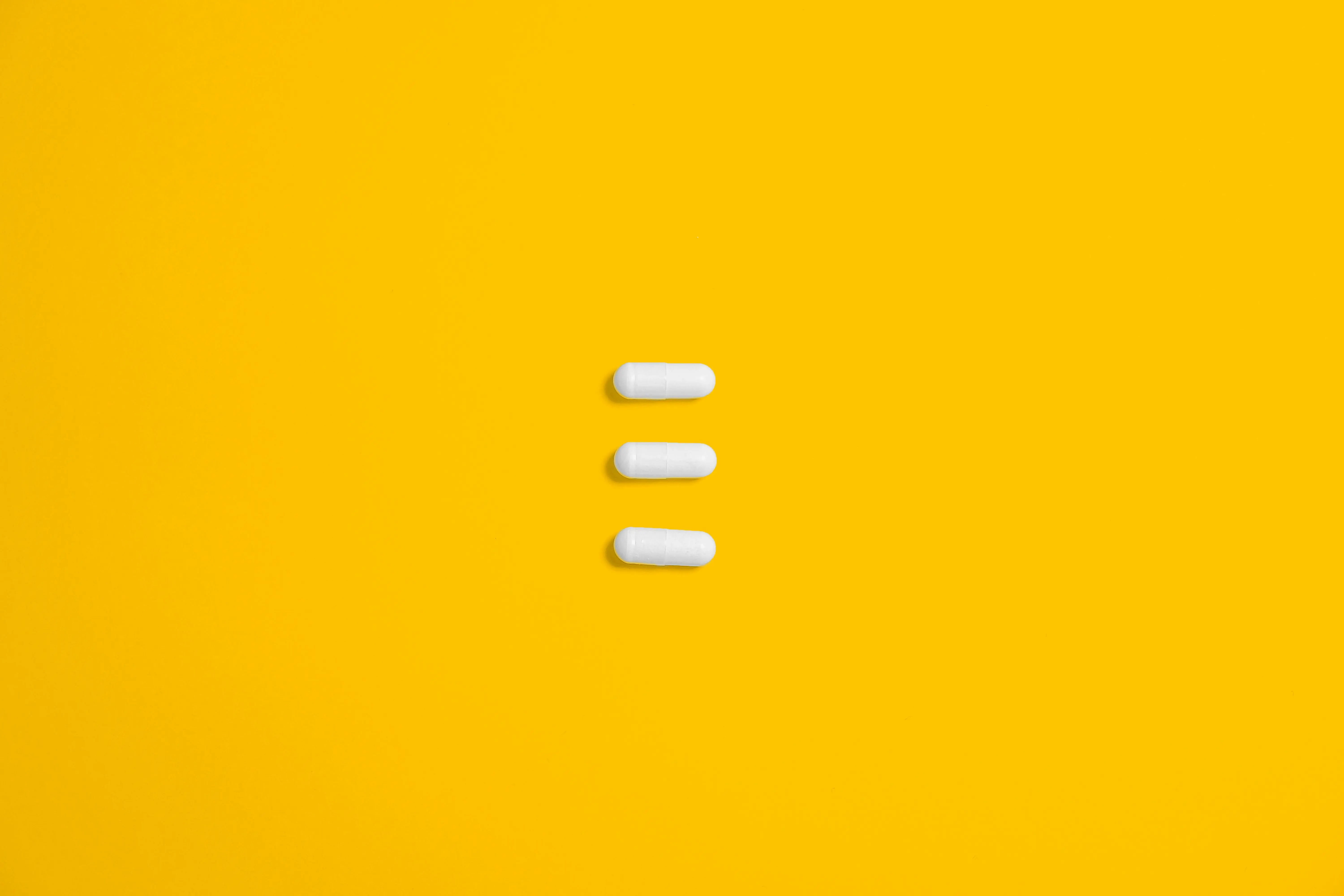 drei Pillen auf gelbem Untergrund