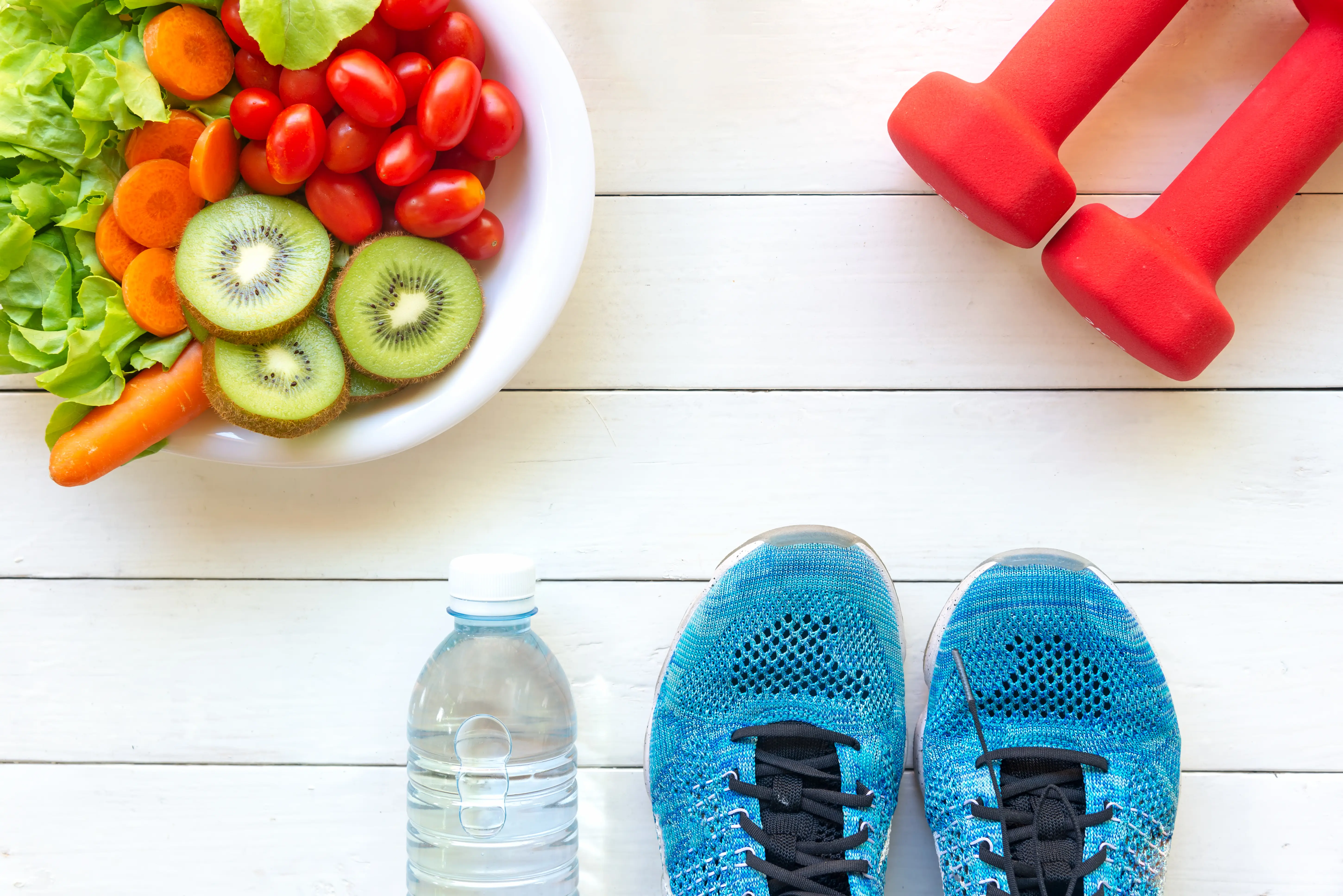 Teller mit Kiwi und Tomaten, Hanteln, Sportschuhe, Wasser