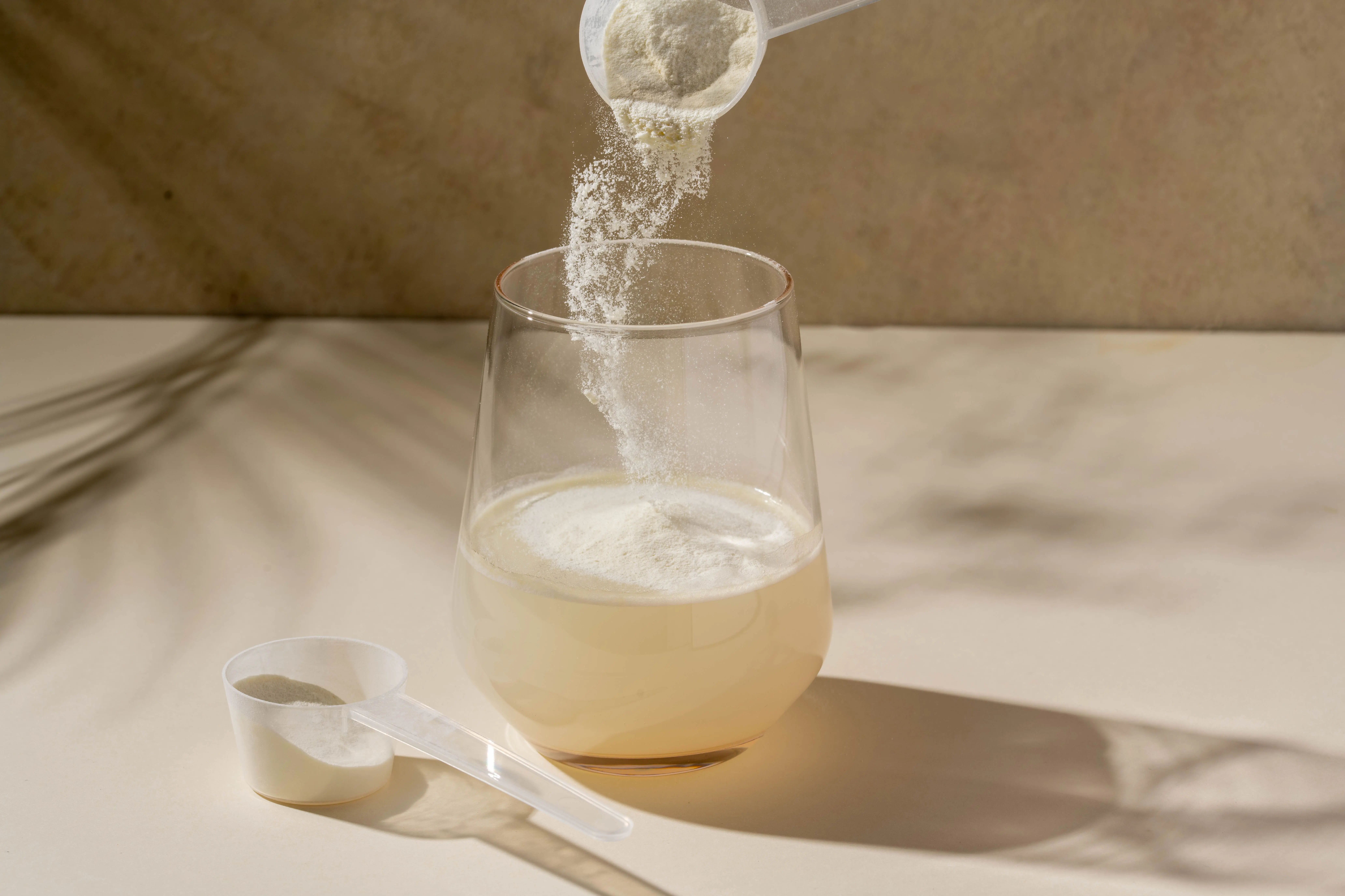 weißes Pulver wird in Wasserglas geschüttet