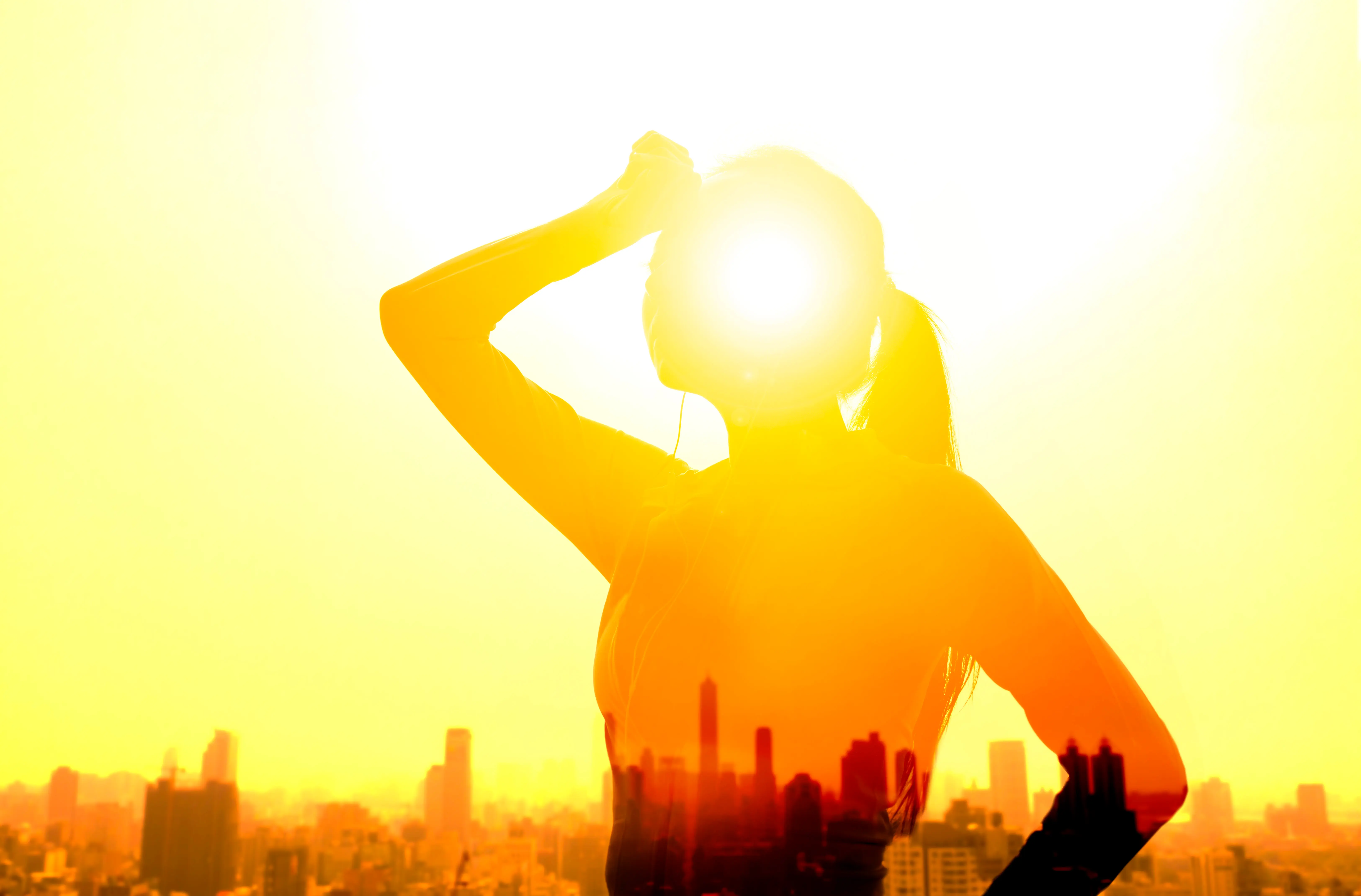 Strategien gegen Hitze Frau im Sonnenlicht vor Häuserkulisse